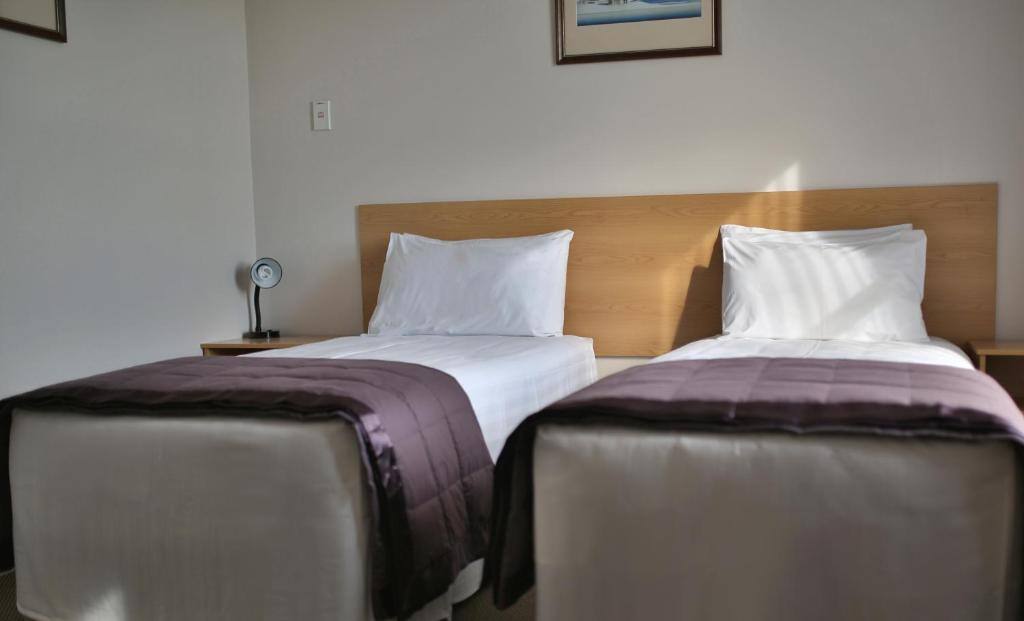 Two single beds with timber headboard and bedside lamp